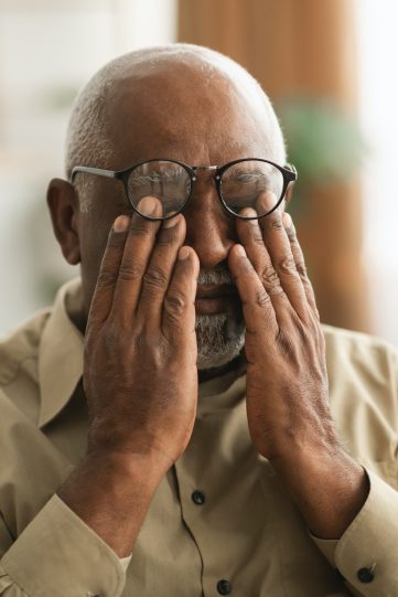 Senior African Man Rubbing Eyes Wearing Eyeglasses Having Glaucoma Indoors