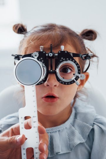 Little girl in eyewear in ophthalmology clinic have test of vision