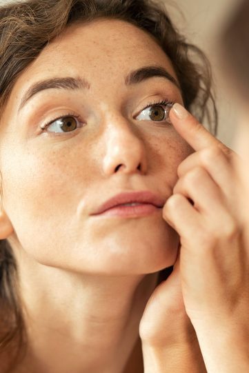 Woman applying contact lens in bathroom