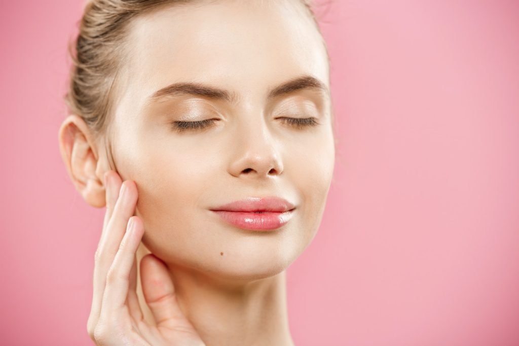 Beauty skin Concept - Beautiful Young Caucasian Woman with Clean Fresh Skin look away with pink