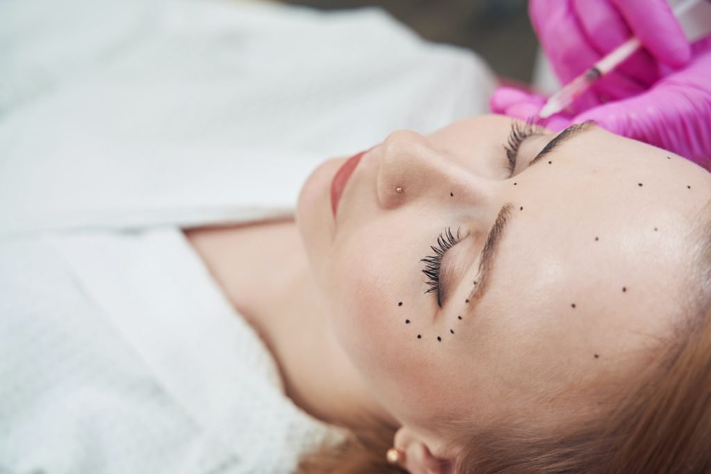 Elegant female is getting biorevitalization procedure in aesthetic center